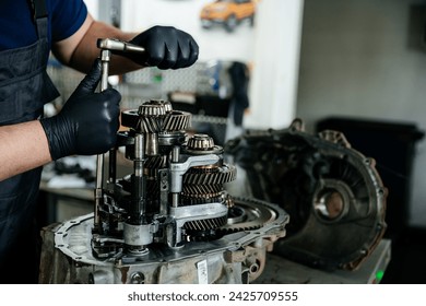 Repair of the manual gearbox of the car at the service station, focus on the disassembled mechanism, which the hands of the craftsman are engaged in - Powered by Shutterstock