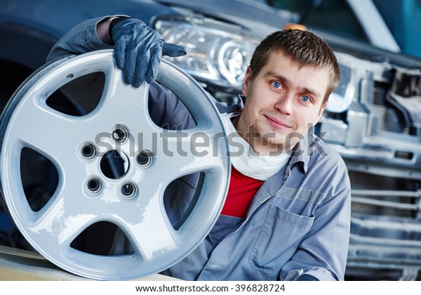repair mechanic worker with light alloy car wheel\
disk rim