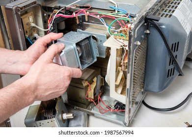 Repair Of The Microwave Oven. A Men Replaces A Magnetron.