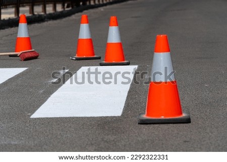 Repair a pedestrian crossing on an asphalt surface on a city street. Work on road. Construction cone.