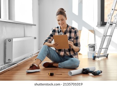 Repair, People And Real Estate Concept - Woman With Clipboard Sitting On Floor At Home