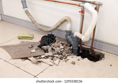 Repair plastic polypropylene gray sewer pipes in the hole in the brick floor with broken tiles. Concept of pipe replacement, water leakage, transfer of water supply, sinks - Shutterstock ID 1295538136
