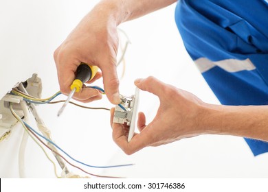 repair, renovation, electricity and people concept - close up of electrician hands with screwdriver fixing socket