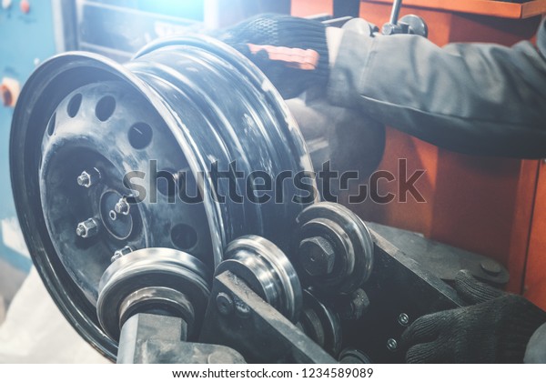 Repair and restoration
of car wheel drive by mechanic master on professional machine
equipment tool in car repair garage service, close up with light
effect, toned
