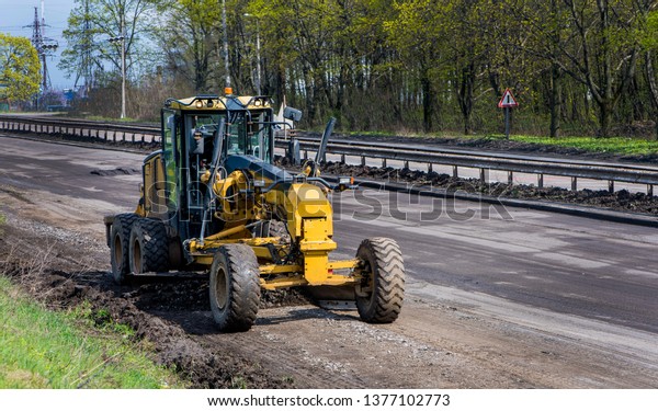 Repair\
the road. Special road equipment in work.\
Grader.