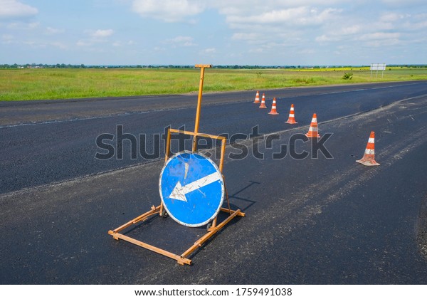 Repair of roads in Ukraine. Road cones and\
road signs on the new asphalt. Copy\
space.