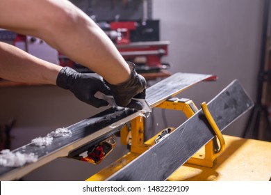 Repair, service and people concept - a man repairing the ski by rubbing a paraffin - Shutterstock ID 1482229109