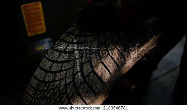 Repair service for wheel tire of car.\
Man show outside place of damage marked with\
chalk.