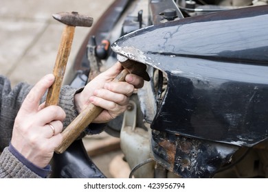 Repair Service Worker Fix Damaged Car After Crash On The Road. Working With Hammer To Align Metal Body.