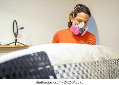 Repair shop with a latin man working in with a surfboard - Powered by Shutterstock