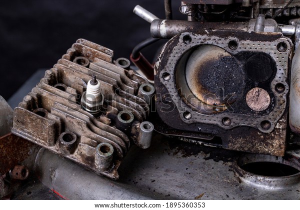 Repair of a small internal combustion engine\
from a lawn mower. Head, cylinder and piston of a four-stroke\
engine. Dark background.