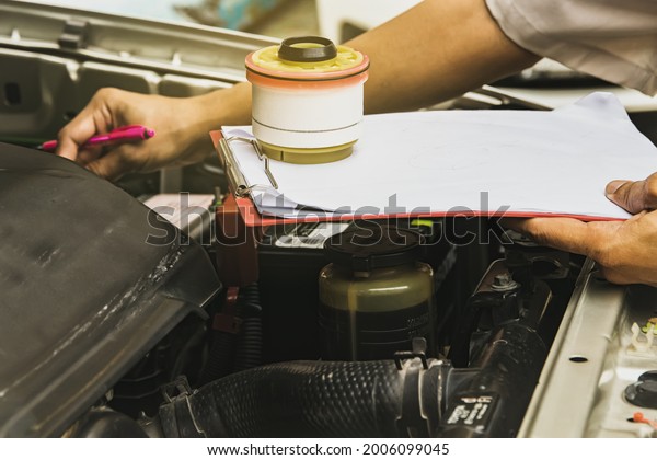 Repair work, check the condition of\
the car : Male mechanic inspects a pickup truck diesel fuel filter\
to replace a new one that is due to replace the old\
one.