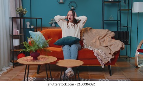 Repair work at neighbours concept. Irritated woman sit on sofa cover ears with hands annoyed by noisy neighbors suffers from headache wishes silence. Thin walls at home, flat without sound insulation