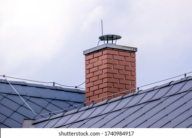 repaired brick chimney in a forest hut with dark roofing