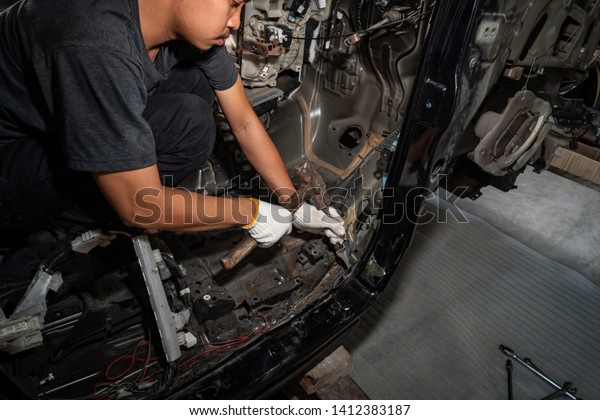 The repairer\
of the car body uses a hammer to break the damaged iron. ,Auto body\
repair series : Fixing car\
body