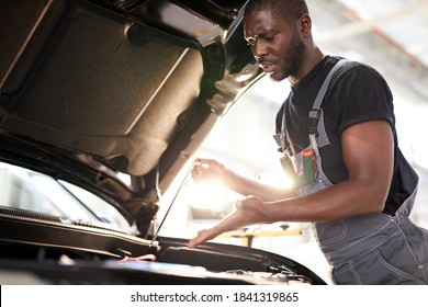 repairing in action. hardworking guy employee in uniform works in the automobile salon, confident auto mechanic is professional worker of service
