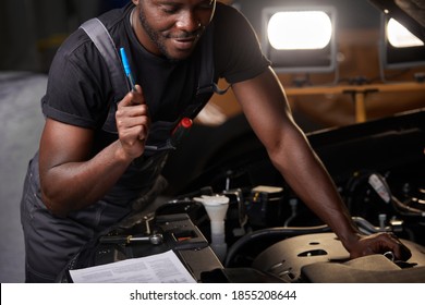 repairing in action. hardworking guy employee in uniform works in the automobile salon, confident auto mechanic is professional worker of service