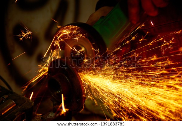 repairing auto in car workshop - repairer cut\
metal on car by angle grinder with\
sparks