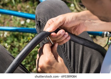 Repairing Bicycle Tube Outdoors During Trip. Close Up Image Of Person Using Glue To Repair Inner Tube Of Bicycle Wheel On The Road