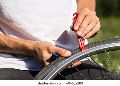 Repairing bicycle wheel outdoors during trip. Close up image of persons hands using tire levers to replace inner tube of bicycle wheel - Powered by Shutterstock