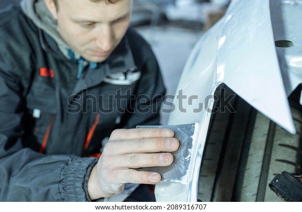 Repairing car body by puttying close up work\
after the accident by working sanding primer before painting. , The\
mechanic repair the car , Using plastic putty ,Prepare surface for\
spray painting.