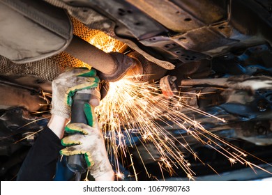 repairing of corrugation muffler of exhaust system in car workshop - repairer cuts old silencer on car by angle grinder - Powered by Shutterstock