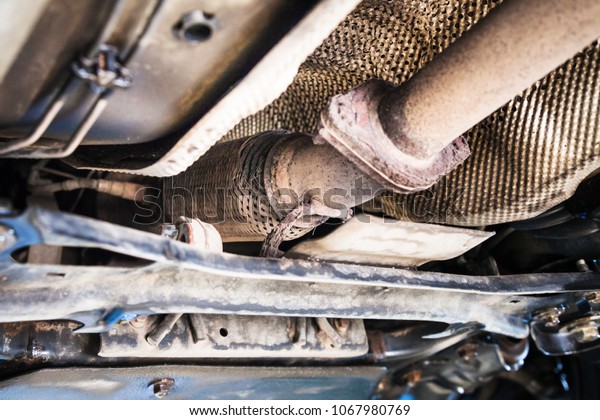 repairing\
of corrugation muffler of exhaust system in car workshop - bottom\
view of old broken corrugation muffler on\
car