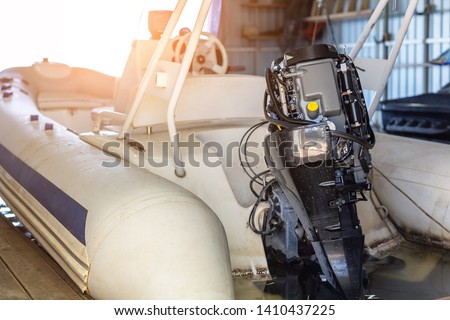 Repairing inflatable motorboat engine at boat garage. Ship engine seasonal service and maintenance. Vessel motor with open cover