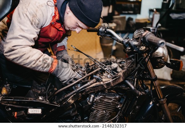 repairing a motorcycle in the garage, a man\
in the garage is repairing the fuel\
system.