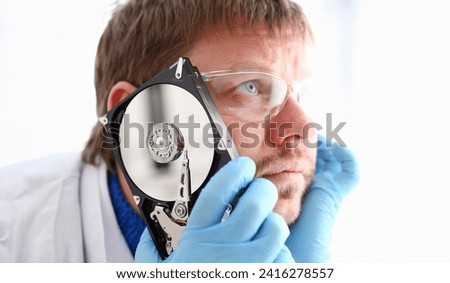 Repairman attached the hard drive of the computer to his ear. Listens to knock and crack reveals the problematic problems and ringing affecting correct operation of hard drive, tests and repairs.