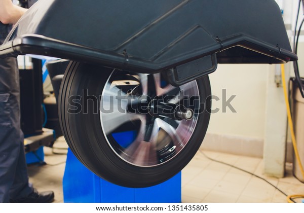 repairman balances the wheel\
and installs the tubeless tire of the car on the balancer in the\
workshop.