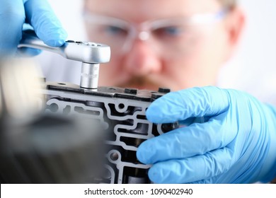 Repairman car-care center on repair of automatic transmissions holds in hand horn key carries out disassembling assemblage hydroblock detail carries diagnostics makes an estimation of working capacity - Shutterstock ID 1090402940