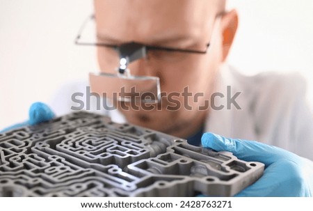 Repairman car-care center on repair holds in hand automatic transmissions carries out disassembling glasses magnifying lens microscope assemblage hydroblock detail carries diagnostics makes estimation