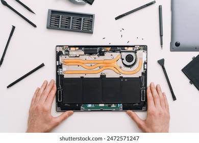 Repairman change battery in laptop. Engineer install new hard drive disk in computer, flat lay. Man fixing broken notebook in warranty service, table top view. Technician upgrade computer components - Powered by Shutterstock