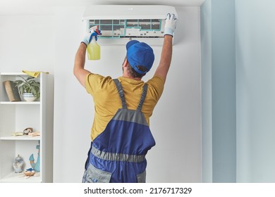 Repairman Cleaning And Fixing Indoors AC Unit.