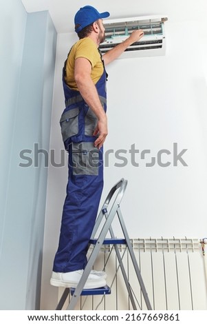 Repairman cleaning and fixing indoors AC unit.