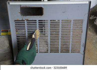 Repairman   Cleaning The Front Cover Of A Gas Furnace Before Re-installing . 