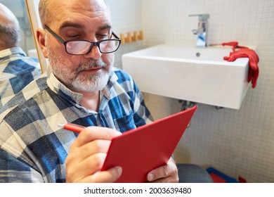 Repairman With Clipboard In Bathroom Writes Quotation For Repair Service Cost