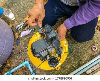 Repairman Fixes The Automatic Water Pump And Installing A New Tank With Tools At House. Maintenance Service Concept.