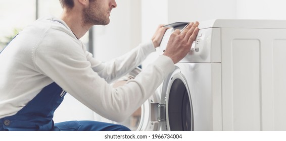 Repairman fixing a washing machine, he is adjusting a knob on the control panel - Shutterstock ID 1966734004