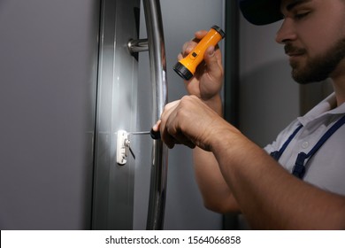 Repairman with flashlight fixing door lock, closeup