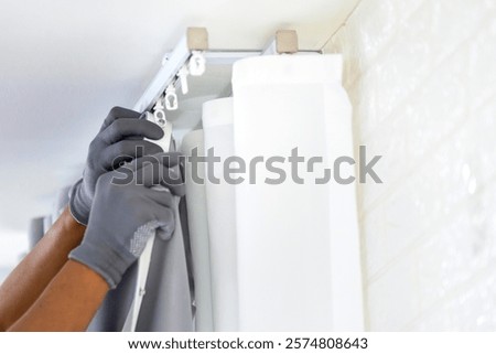 Repairman installs a curtain rod and hangs curtains in the house, Worker hanging window curtain
