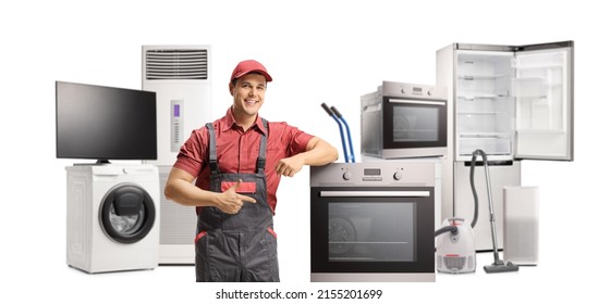 Repairman leaning and pointing to an electric oven with other home appliances in the back isolated on white background