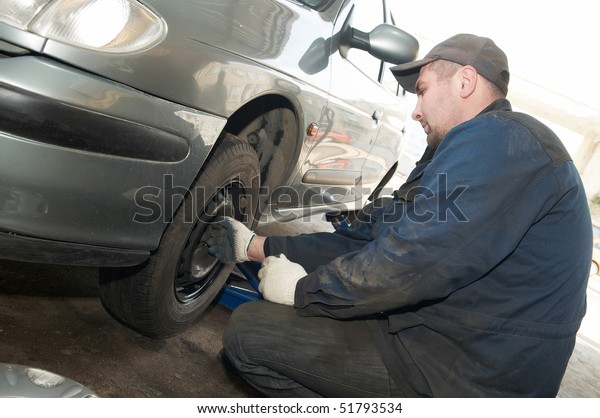 repairman making tyre fitting with air compressed\
wrench (screwing up\
bolts)