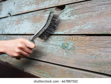 Repairman Remove The Old Paint From The Wooden Surface With  Wire Brush.