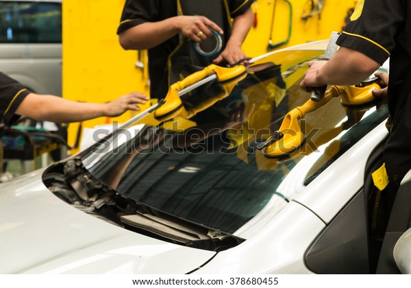 Repairman is repairing\
windshield of the car