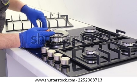 A repairman repairs a gas stove close-up. Repair of appliances in the kitchen room. 