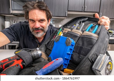 Repairman showcasing his every day tool bag on a kitchen countertop. 