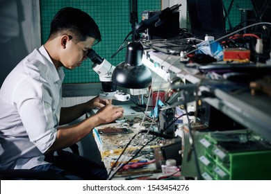 Repairman using microscope when fixing small details in smartphone