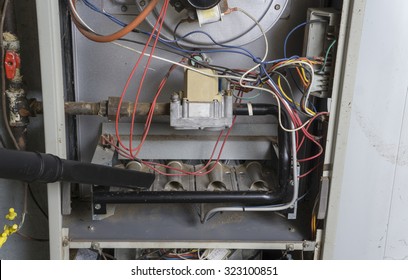 Repairman Using A Vacuum Inside Of A Gas Furnace. 